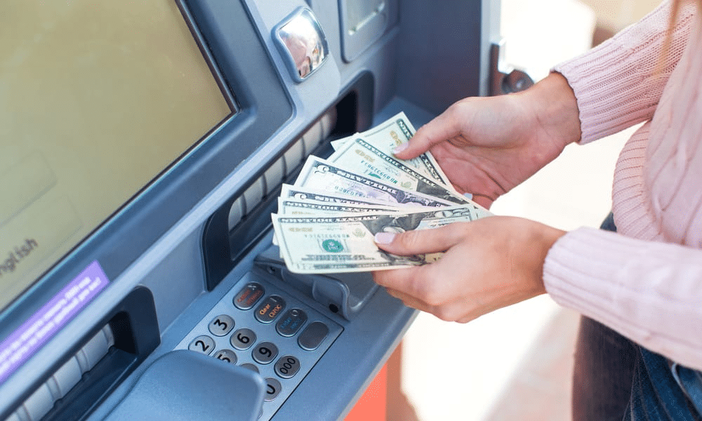 Woman with dollars in front of ATM