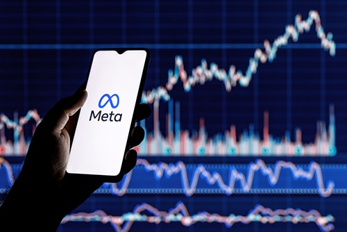 Smartphone with Meta logo on the background of stock chart.